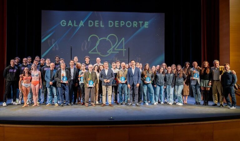 Deportistas, entrenadores, y más personas vestidas para la ocasión en una gala de premios en Tres Cantos, reunidas en un salón repleto de gente y ambiente festivo.