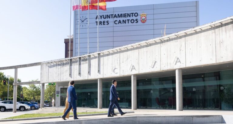 Fachada del Ayuntamiento de Tres Cantos con banderas ondeando y autoridades accediendo al edificio.