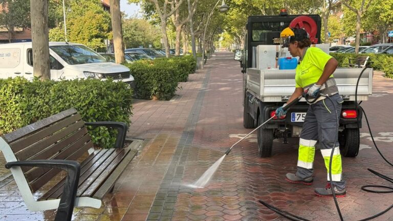 Operarios realizando limpieza urbana intensiva con agua a presión en una avenida principal.